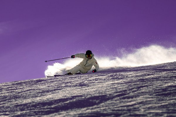 Skifahrer carvt mit Schneefahne über die Piste – Wintersport-Fachgeschäft Alpin Basis in Frankfurt