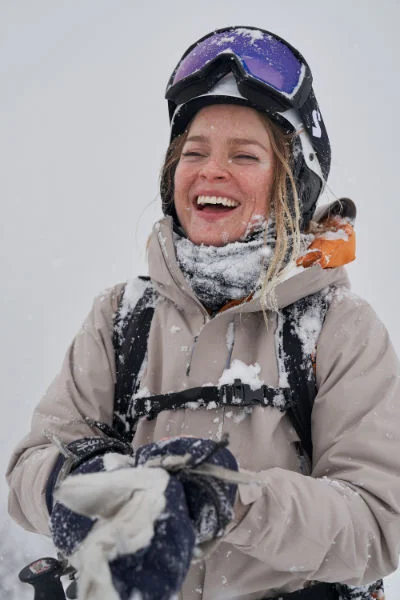 Funktionale Skijacke – hochwertige Ski Bekleidung Lachende Skifahrerin in funktionaler Skijacke – hochwertige Ski Bekleidung für maximale Wärme und Schutz