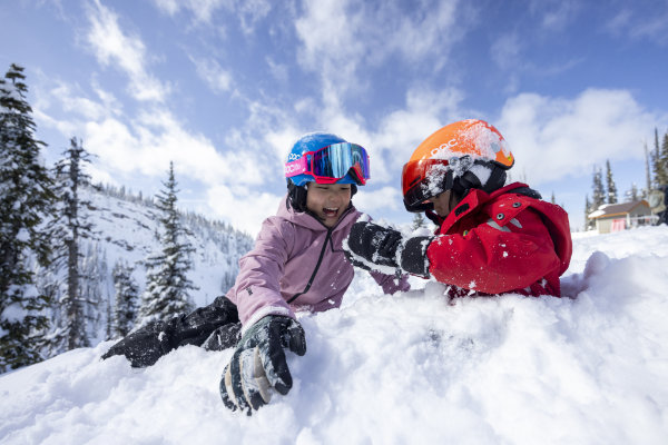 Kinder mit farbigen Skihelmen spielen im Schnee – hochwertige Skibrille und Ski Sicherheit Ausrüstung für sicheres Skifahren