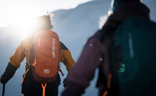 Zwei Wintersportler mit Lawinensicherheitsrucksäcken im Gebirge – wichtige Ski Sicherheitsausrüstung für Skitouren