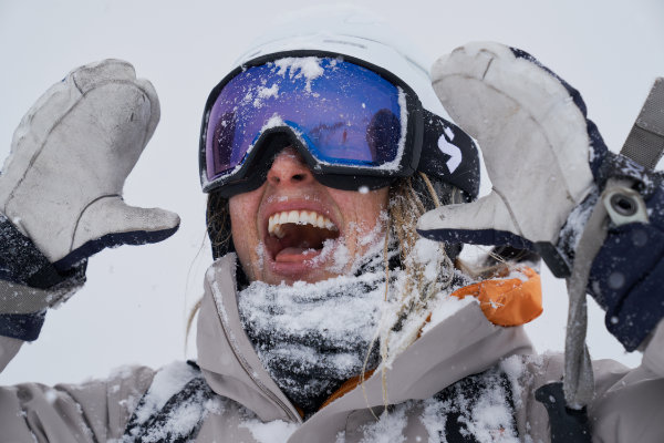 Verschneite Wintersportlerin mit hochwertiger Skibrille und Skihelm – essentielle Ski Sicherheitsausrüstung für jede Abfahrt