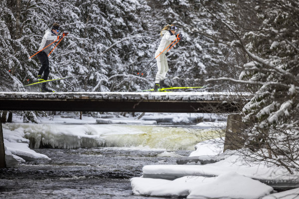 Zwei Wintersportler beim Langlauf über eine verschneite Brücke – hochwertige Skier für sportliche Ausdauer im Winter