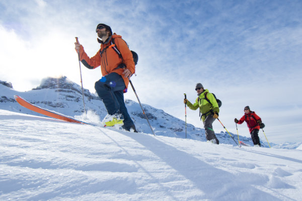 Drei Wintersportler steigen mit hochwertigen Skiern bergauf – Premium Ski für sportliche Alpin- und Tourenabenteuer