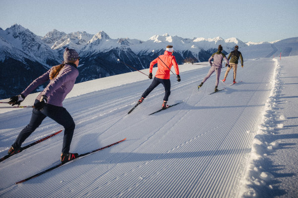 Langlaufgruppe in funktionaler Ski Bekleidung auf präparierter Loipe – hochwertige und atmungsaktive Skibekleidung für Langlauf