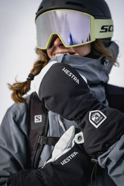 Skifahrerin in funktionaler Premium Skibekleidung mit warmen Ski-Handschuhen – hochwertige Skijacke für anspruchsvolle Bedingungen