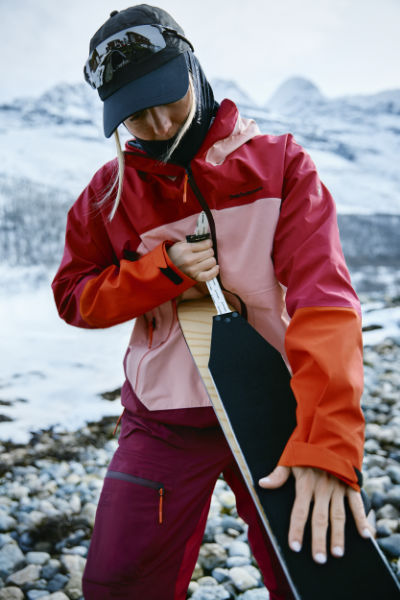 Skifahrerin in funktionaler Skijacke pflegt ihre Ski – hochwertige Ski Bekleidung für anspruchsvolle Freeride-Tage