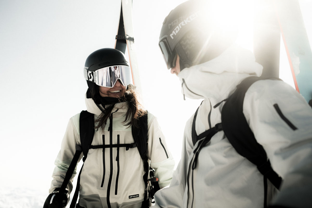 Zwei Skifahrer in funktionaler Premium Skibekleidung mit Helm und Brille – hochwertige Skijacke und Skihose im alpinen Einsatz.